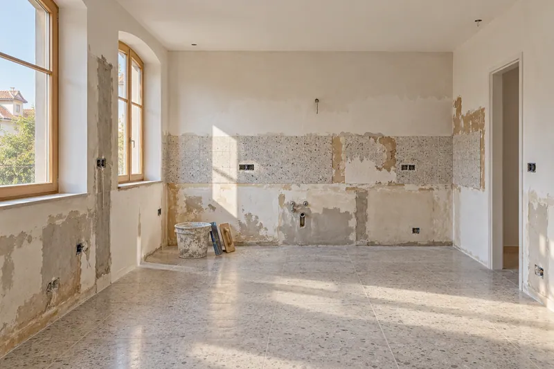 Visualización conceptual IA: Cocina sin muebles con paredes en preparación y zonas de enlucido.